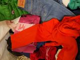a basket full of clothes on a bed with a white blanket