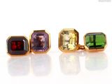 three different colored gems are displayed in a row on a white surface