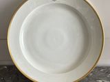 a close up of a white plate with gold trim on a marble surface