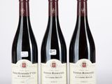 trois bouteilles de vin rouge sont alignées sur une surface blanche