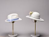 pair of white hats on a marble base with a blue ribbon