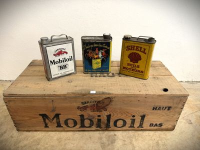 three cans of oil sitting on top of a wooden box
