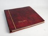 un gros plan d'un livre rouge posé sur une surface blanche