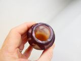 une personne tenant un petit vase violet à la main
