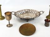 a silver bowl and other brass objects on a white surface