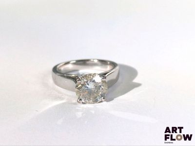 une image d'une bague en diamant posée sur une surface blanche