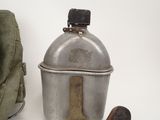 a small metal container with a wooden handle next to a bag
