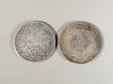 two silver coins sitting next to each other on a white surface