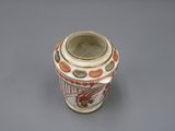 un vase blanc orné de motifs orange sur un fond gris