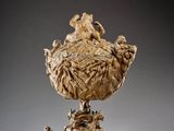 an image of a golden vase with animals on top of it