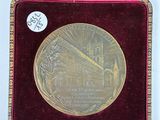 a gold medal in a red case on a white surface