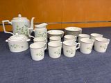many cups and saucers on a table with a teapot