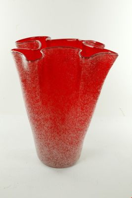 un vase rouge posé sur une surface blanche