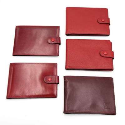 un lot de quatre portefeuilles en cuir rouge et marron sur fond blanc