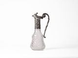 an old fashioned glass pitcher with a handle on a white surface