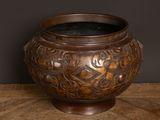 a brown vase sitting on a wooden table with a black background