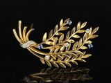 an image of a gold and diamond broochle on a black surface