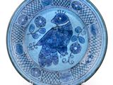 a blue plate with a bird on it on a stand