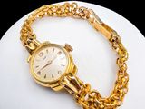 a gold watch with a chain around it on a white plate