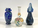 three glass vases are lined up on a white surface