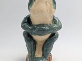 a ceramic frog that is sitting on top of a toilet