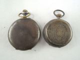 two antique pocket watches sitting on a white surface