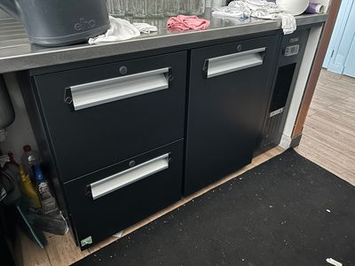 une armoire noire avec deux tiroirs, sur laquelle est posé un pot