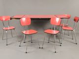 Six chaises rouges sont disposées autour d'une table au plateau noir.