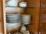 many plates and cups in a cabinet with glass shelves
