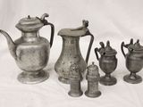 a group of silver vases and cups on a table