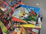 pile of comic books sitting on top of a table next to a laptop computer