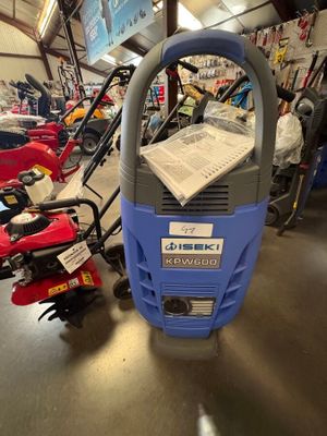 une nettoyeuse haute pression bleue et grise posée sur le sol d'un garage
