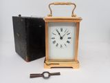 une petite horloge posée à côté d'une boîte contenant une clé