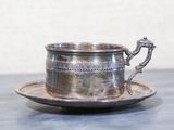 une tasse et une soucoupe en argent posées sur une table