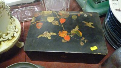 une boîte noire décorée de fleurs, posée sur une table