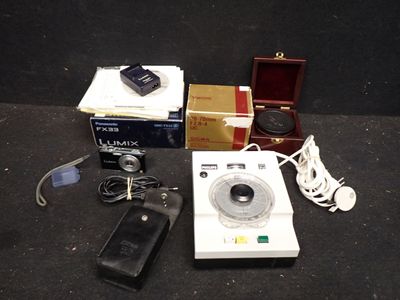 une image représentant un appareil photo, un téléphone portable et d'autres appareils électroniques posés sur une surface noire