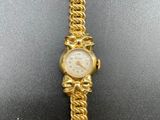 a close up of a gold watch with a chain around it