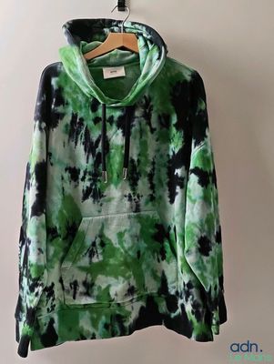 un sweat à capuche tie-dye vert et noir suspendu à un cintre