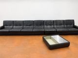 un canapé en cuir noir et une table basse dans une pièce aux murs blancs