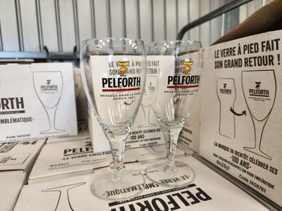 Plusieurs verres à vin vides sont posés sur une table devant des caisses de bière