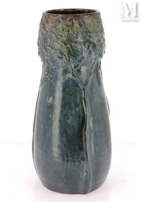 un vase vert posé sur une surface blanche
