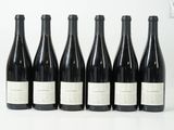 six bouteilles de vin sont alignées sur une surface blanche