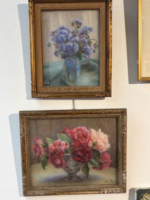 trois tableaux accrochés au mur à côté d'un vase de fleurs