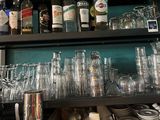 many glasses and bottles on a shelf in a bar