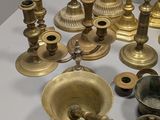 many different types of brass candles on the table