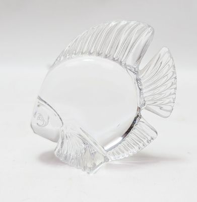 une figurine de poisson en verre posée sur une surface blanche