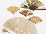un assortiment d'éventails chinois et d'autres objets posés sur un fond blanc