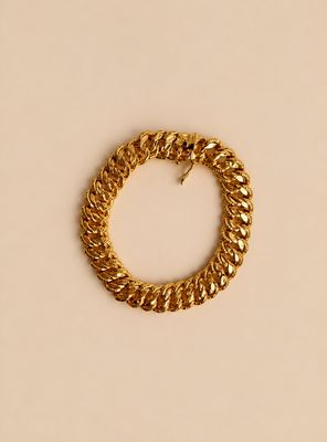 un bracelet en chaîne d'or avec un fermoir, sur fond beige