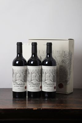 trois bouteilles de vin posées sur une table, à côté d'une boîte