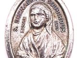 un gros plan d'une médaille en argent sur laquelle figure une image de Jésus